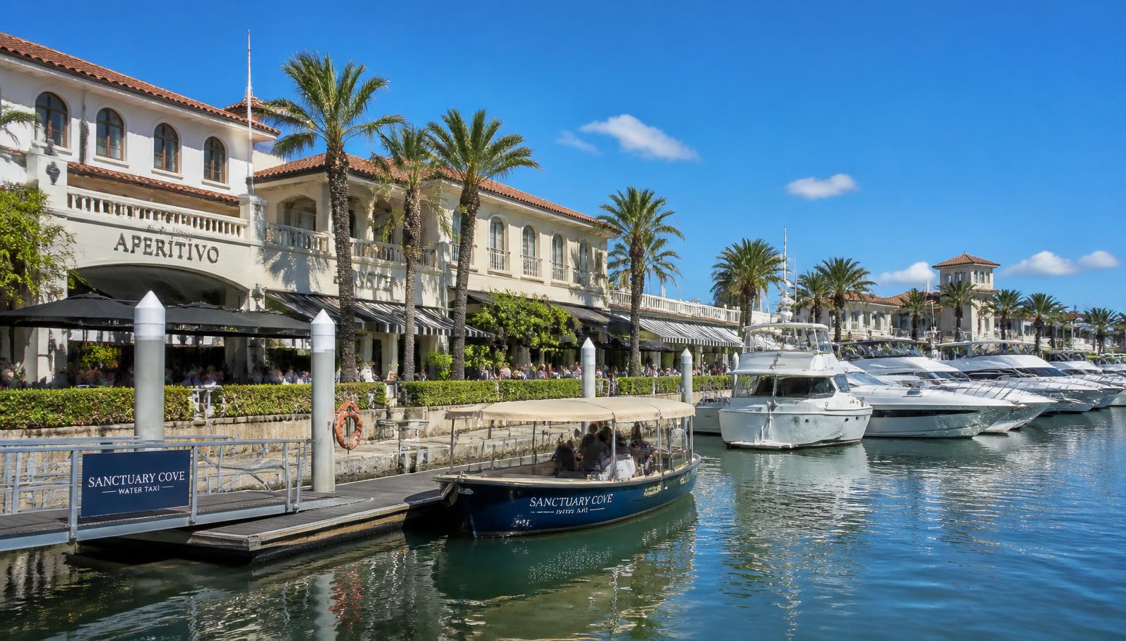Water taxi at the pontoon of a marina village lined with waterfront restaurants on the northern Gold Coast