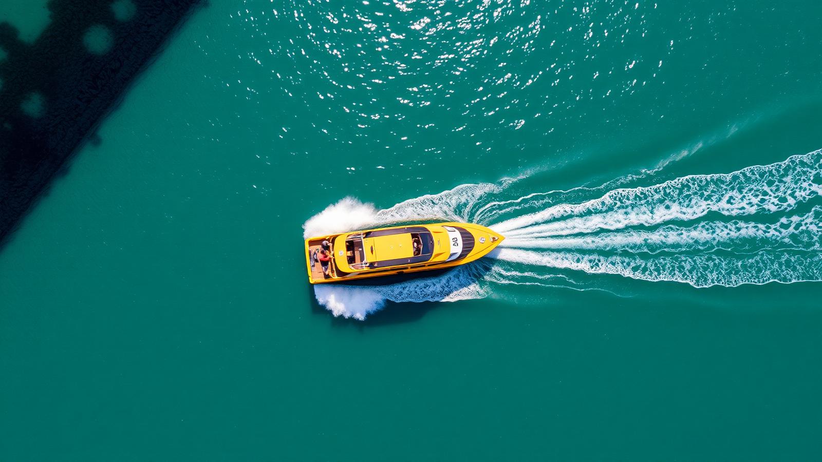 Aerial view of a yellow water taxi cutting across turquoise Australian harbour water